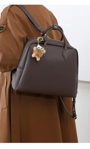 Dettaglio borsa tote marrone scuro in pelle martellata con spallacci regolabili sul cappotto