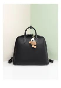 Dettaglio della borsa tote in pelle nera con ciondolo di peluche e manico superiore