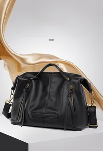 Detail of black pebbled leather tote bag with vintage gold hardware on a satin background