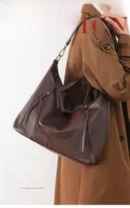 Detail of dark brown lychee leather tote bag with long tassel zippers and bronze hardware
