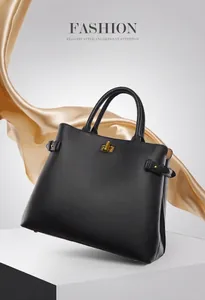 Detail of black tote bag with gold twist lock and silk scarf on white podium