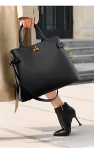 Detail of elegant black leather tote bag with gold twist lock and side strap buckle