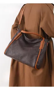 Detail of leather woven handle and rich lychee grain texture on a brown tote bag