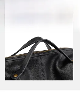 Detail view of black lychee leather handle with gold rivets and smooth metal zipper