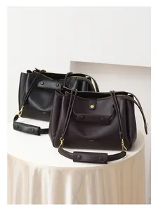 Detalle de bolsos tote de cuero premium en negro y granate con herrajes dorados