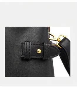 Detail of black lychee leather handbag with golden hardware and adjustable side strap