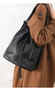 Detail of black pebbled leather backpack with drawstring closure and side zipper pocket
