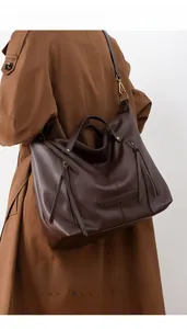 Detail of a dark coffee tote bag with tassel zipper and pebble leather texture for daily use