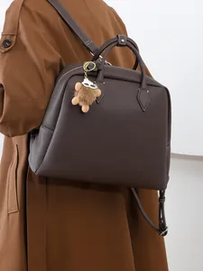 Zaino in pelle martellata marrone scuro con ciondolo di peluche mostrato lateralmente