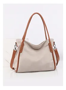 Detail of soft faux leather tote bag showing stitching and brown strap on marble surface
