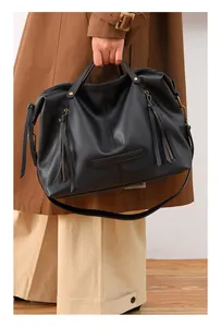Detail of black pebbled leather tote bag with stylish long tassels and metal zipper