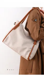 Detail of soft leather tote bag with contrast stitching and shoulder strap on model