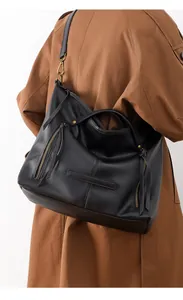 Detail of black pebbled leather tote bag with zip pockets and fringes on model