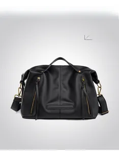 Close-up of black textured leather tote bag featuring parallel zippers and bronze rivets