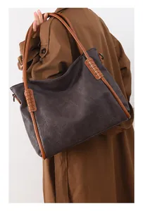 Detail of a large brown tote bag with slim shoulder straps and fine leather stitching