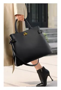 Detail of black leather tote bag with gold twist lock and adjustable side buckles