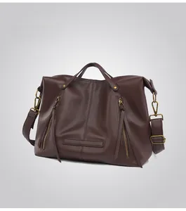 Detail view of coffee brown tote bag with pebbled leather texture and dual zip tassels