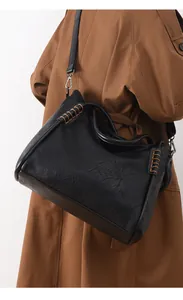 Detail of black tote bag featuring brown hand-stitched accents on the leather handle
