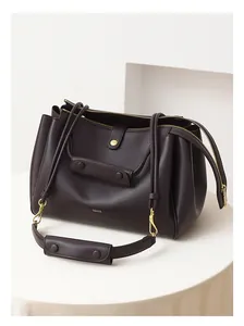 Detalle del bolso tote de cuero marrón chocolate liso con cremalleras y logo dorado