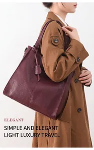 Detail view of burgundy lychee grain leather tote bag with elegant shoulder strap and charm