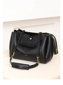 Detalle del bolso tote de cuero negro mate con herrajes dorados y logotipo GEXYA