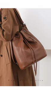 Side view of large brown lychee grain leather drawstring backpack with metal eyelets