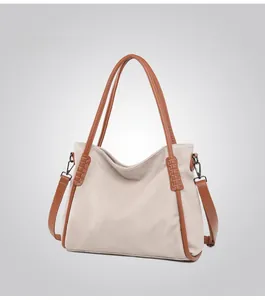 Detail of minimalist tote bag with contrast brown piping and metallic hardware