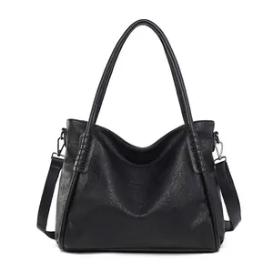 Detail view of large black tote bag featuring soft leather texture and dual shoulder straps