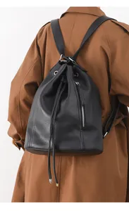 Detail of black pebbled leather drawstring backpack with silver side zipper on a model