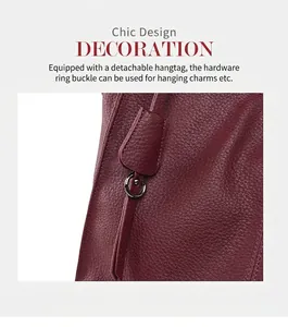 Detail of dark burgundy leather tote featuring a detachable charm and metal ring fastener