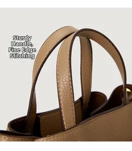 Detail of sturdy handles and fine edge oil finish on brown lychee grain leather tote