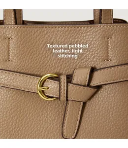 Macro detail of khaki lychee grain leather handbag with tight stitching and gold metal buckle