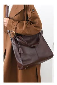 Detail of dark brown tote bag showing textured pebbled leather and elegant tassel charm