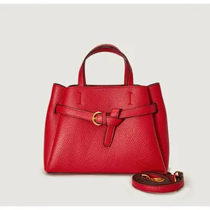 Detail of red pebbled leather handbag with gold buckle and adjustable shoulder strap