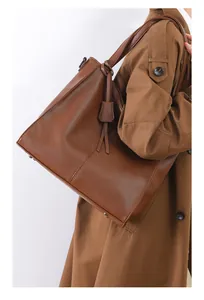 Close-up of brown litchi pattern leather tote bag with long strap and metal studs