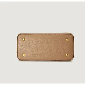 Detail view of brown textured leather handbag base with four protective gold metal studs