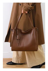 Detailed view of dark brown lychee texture leather tote bag with elegant hanging charm accessory