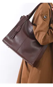 Detail of dark brown leather tote bag with pebble texture and protective metal studs