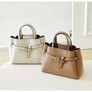 Detailed view of textured leather tote bags in cream and caramel with strap accents
