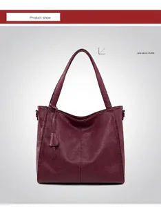 Detail of dark red lychee grain leather tote bag with elegant hanging charm accessory