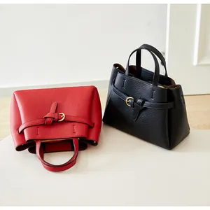 Detailed view of red and black leather handbags with lychee grain texture and metal buckles