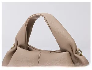 Close-up of soft padded leather handle and gold D-ring on beige cloud handbag