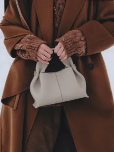 Detail view of beige pleated cloud handbag with fine leather texture and golden buckles