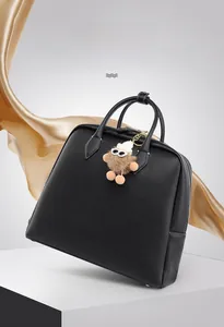 Dettaglio borsa in pelle nera con cerniere metalliche e ciondolo mostro in peluche