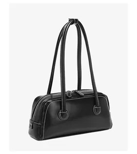 Detalle del bolso bowling vintage de cuero negro con costuras blancas y asas largas