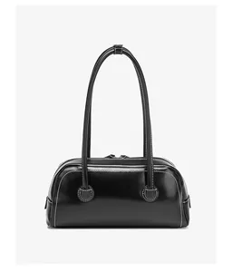 Detalle de bolso bandolera negro brillante con pespuntes blancos y correas delgadas