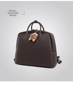 Dettaglio borsa a mano marrone in pelle martellata con forma rigida e ciondolo di peluche
