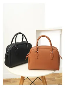 Detail of lychee textured leather tote bags in black and brown with metal zippers