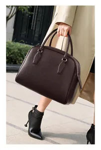 Detail of dark brown lychee leather tote bag with dual handles and silver metal rings