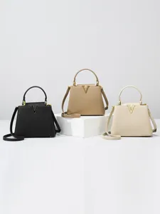 Chic leather crossbody bag with top handle and gold V metal hardware in neutral tones